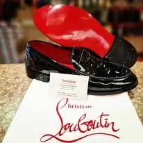 Mocassins vernis noirs à semelle rouge, posés sur leur pochon signature